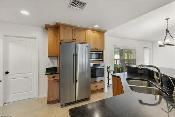 Kitchen featuring an inviting chandelier, light tile flooring, appliances with stainless steel finishes, sink, and pendant lighting