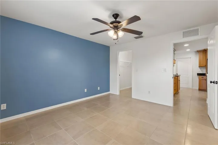 Empty room with ceiling fan and light tile floors