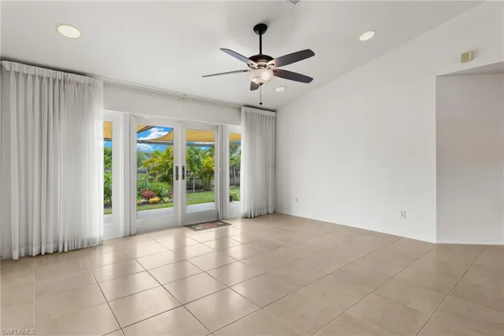 Tiled spare room with french doors, ceiling fan, and vaulted ceiling
