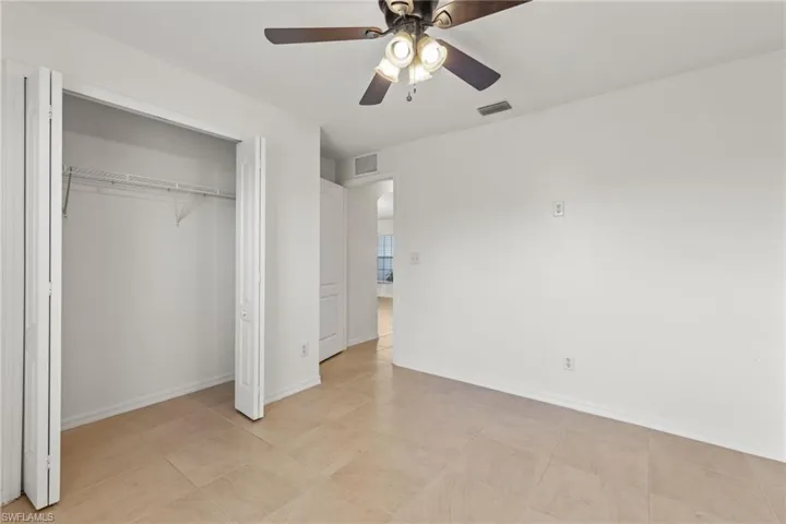 Unfurnished bedroom featuring ceiling fan, a closet, and light tile floors