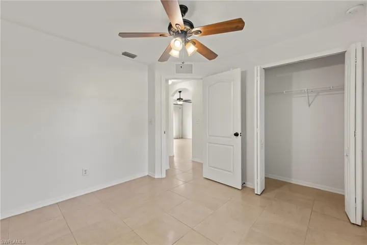 Unfurnished bedroom featuring ceiling fan, a closet, and light tile floors