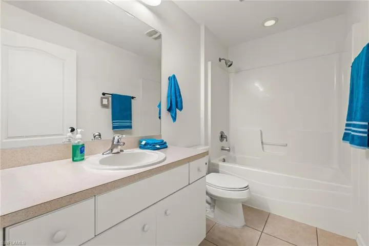 Full bathroom featuring tile floors, large vanity, toilet, and shower / bathing tub combination
