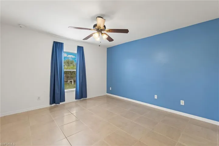 Unfurnished room with ceiling fan and light tile floors