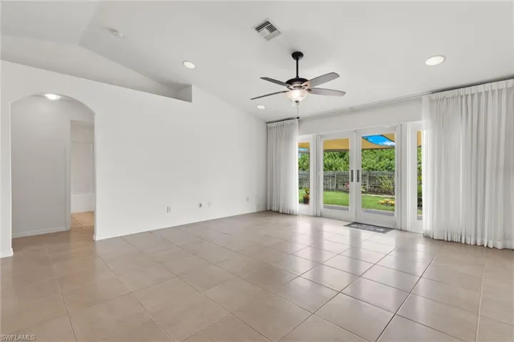 Unfurnished room featuring vaulted ceiling, ceiling fan, light tile flooring, and french doors