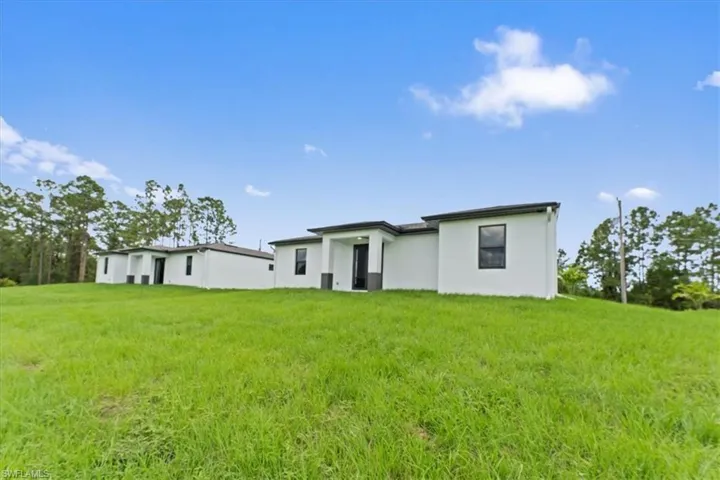 Rear view of property with stucco siding and a lawn