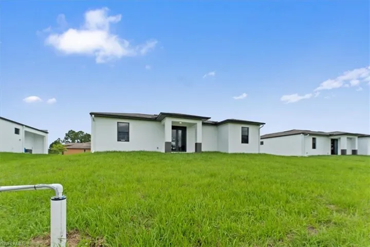 Back of house with stucco siding and a lawn