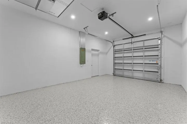 Garage with electric panel, recessed lighting, and a garage door opener