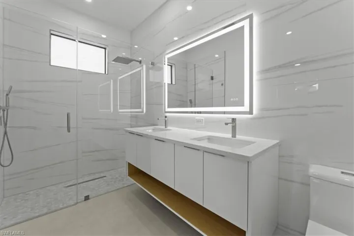 Full bath with double vanity and a marble finish shower