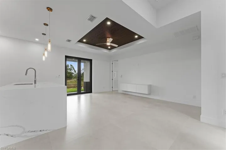 Unfurnished living room featuring french doors, a raised ceiling, recessed lighting, and a ceiling fan
