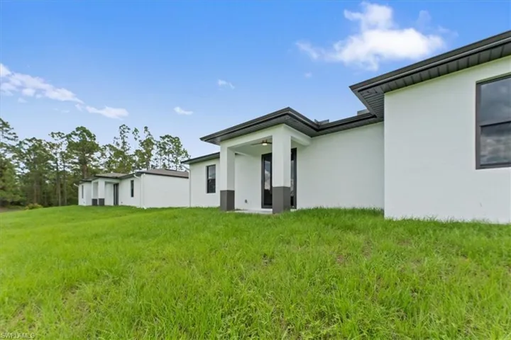Rear view of property featuring a yard, a patio, and stucco siding