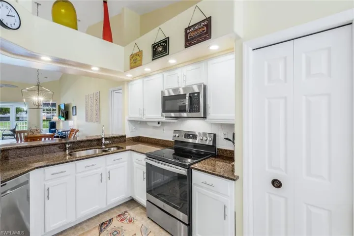 Kitchen featuring Wine Cooler, Pantry, Water Filtration, stainless steel appliances, white cabinetry, recessed lighting, dark stone countertops, and a chandelier