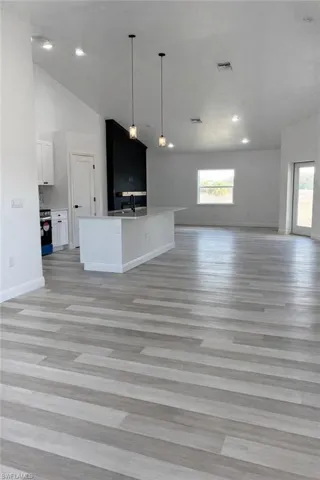 Unfurnished living room with lofted ceiling, light wood-type flooring, plenty of natural light, and recessed lighting