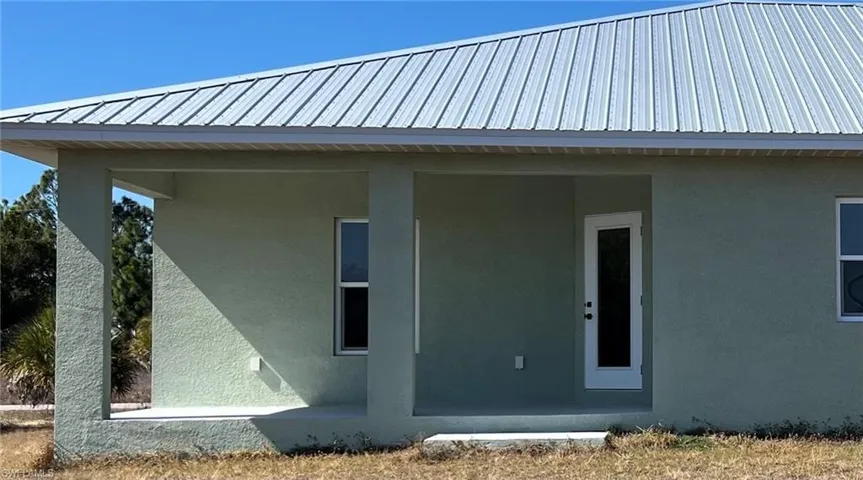 View of side of property with stucco siding and a metal roof