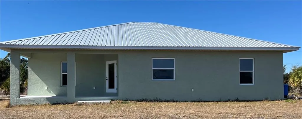 Back of house with stucco siding, a metal roof, and a porch