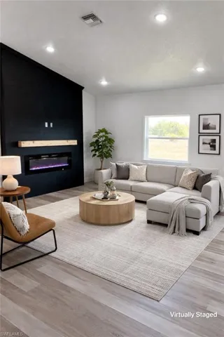 Living room with a glass covered fireplace, light wood-style floors, and recessed lighting