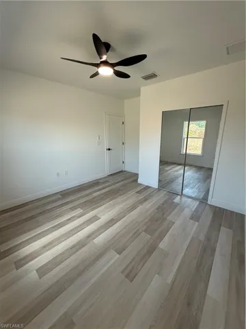 Unfurnished bedroom with light wood finished floors, ceiling fan, and a closet
