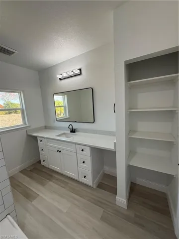 Bathroom featuring vanity, light wood-type flooring, a textured ceiling, and built in shelves