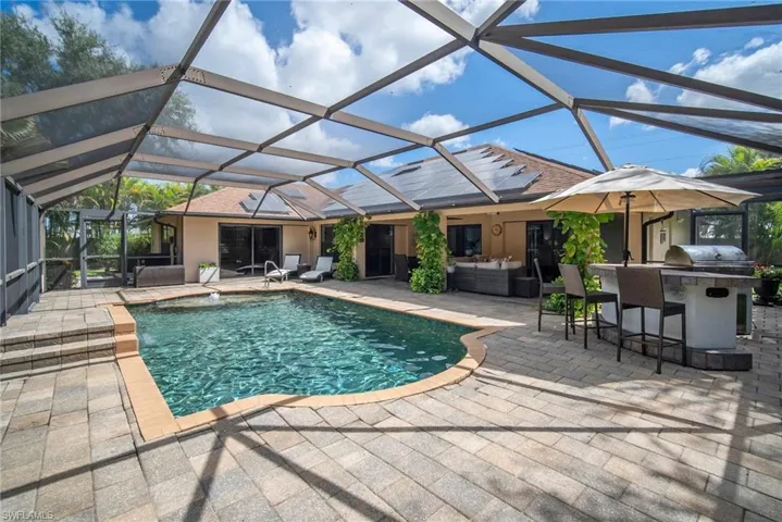 View of swimming pool with a patio, glass enclosure, and exterior bar