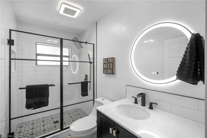 Bathroom featuring vanity, toilet, and an enclosed shower