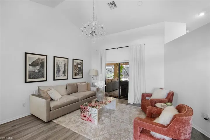 Living room featuring hardwood / wood-style floors, high vaulted ceiling, and an inviting chandelier