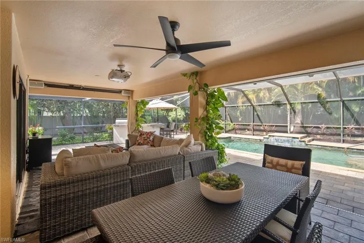 View of patio featuring ceiling fan, an outdoor hangout area, a fenced in pool, and glass enclosure