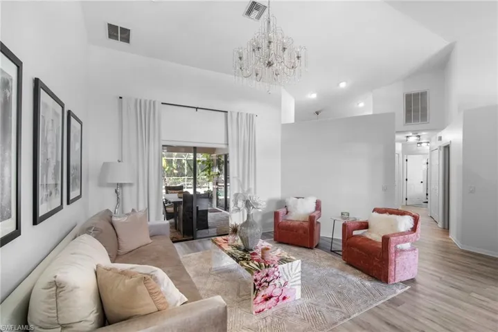 Living room with light hardwood / wood-style floors, a notable chandelier, and high vaulted ceiling