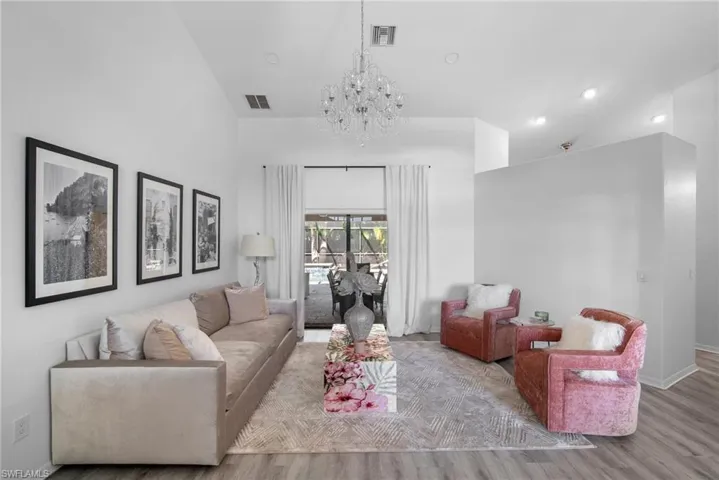 Living room with a notable chandelier, lofted ceiling, and light wood-type flooring