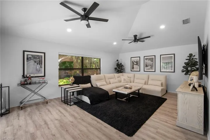 Living room with light hardwood / wood-style flooring, ceiling fan, and vaulted ceiling