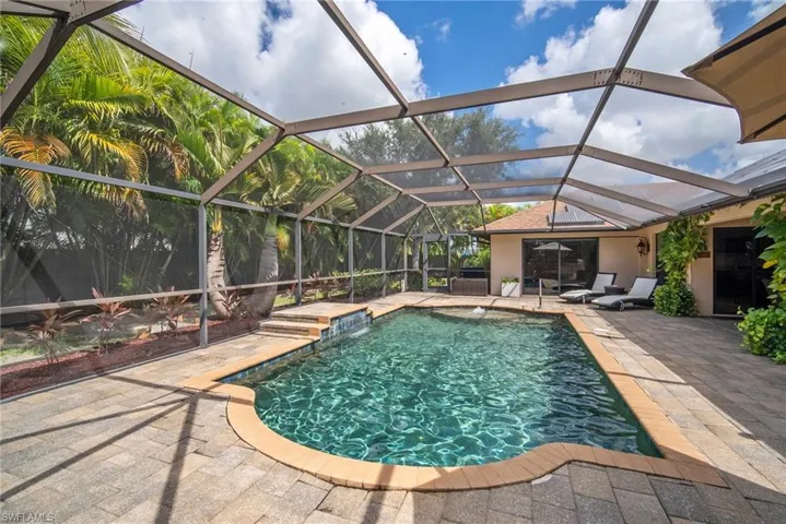 View of pool featuring a patio area, pool water feature, and glass enclosure