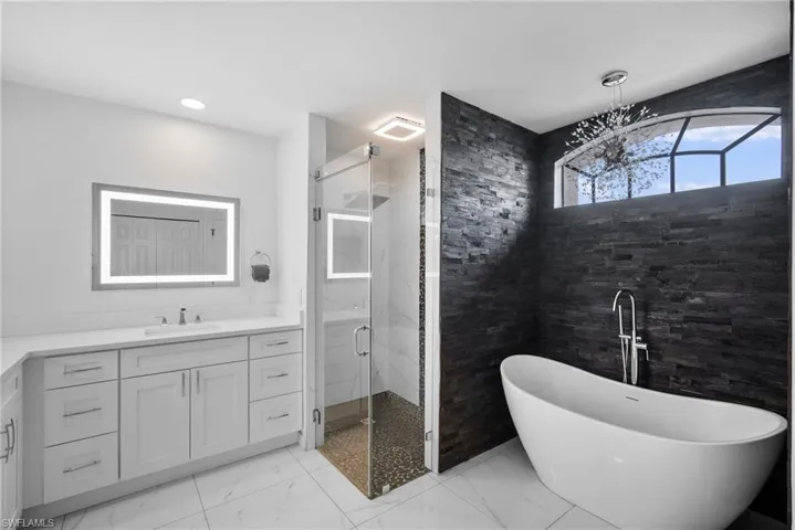 Bathroom featuring shower with separate bathtub, vanity, tile patterned flooring, and tile walls