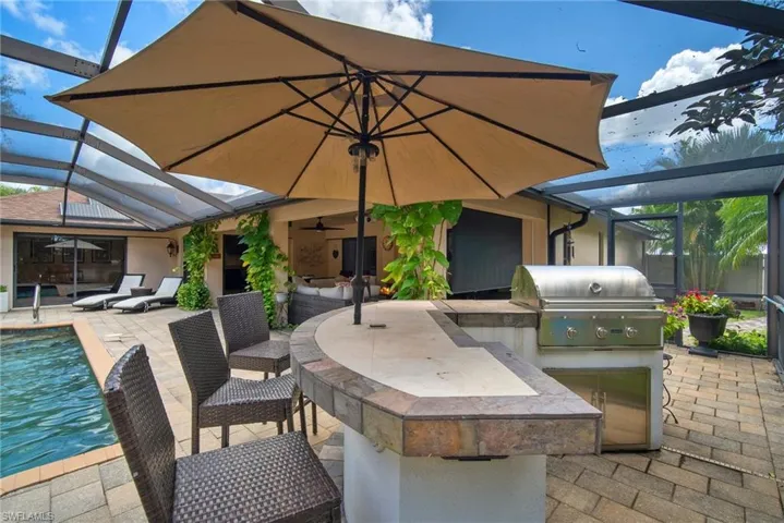 View of patio / terrace featuring area for grilling, a bar, and glass enclosure