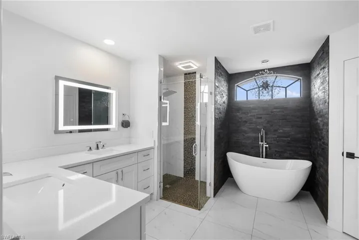 Bathroom featuring tile patterned flooring, tile walls, shower with separate bathtub, and vanity