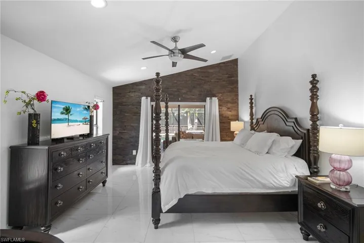 Tiled bedroom featuring high vaulted ceiling and ceiling fan