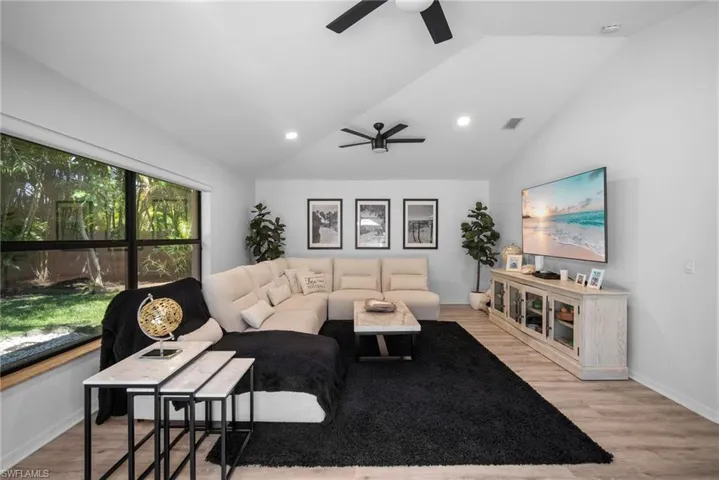 Living room featuring light hardwood / wood-style floors, lofted ceiling, and ceiling fan