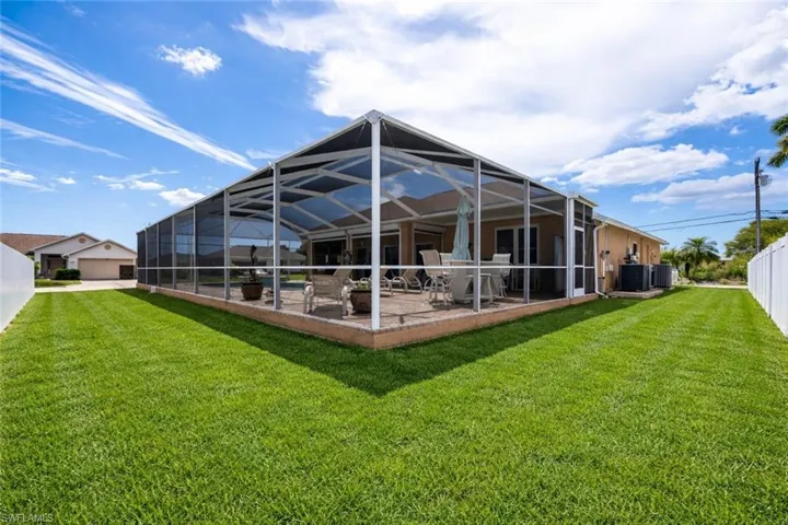 Rear view of house with glass enclosure, a sunroom, and a lawn