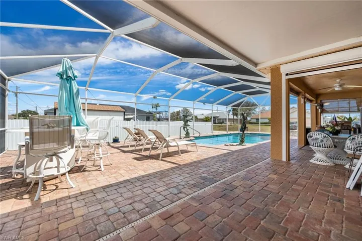 View of swimming pool with patio surround, a lanai, a sunroom, and outdoor dining space