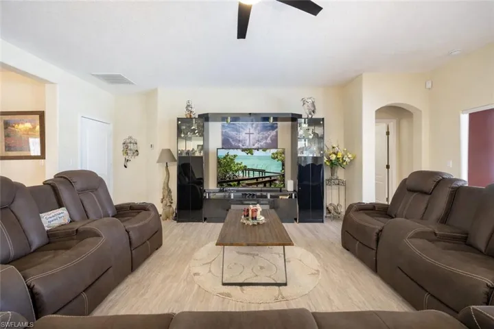 Living room with wood finished floors, a ceiling fan, and arched walkways