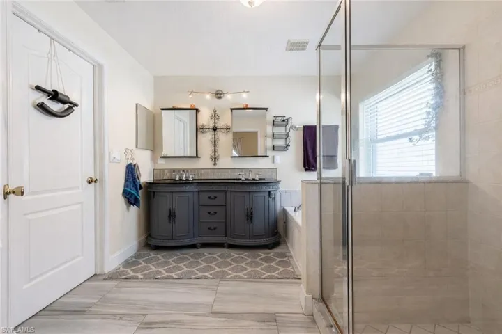 Full bath featuring double vanity and a shower stall