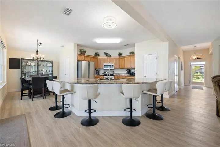 Kitchen with a breakfast bar, stainless steel appliances, a spacious island, and light wood finished floors
