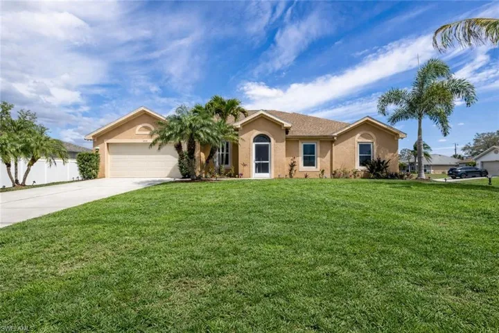 View of front of home with stucco siding, driveway, a front lawn, and a garage