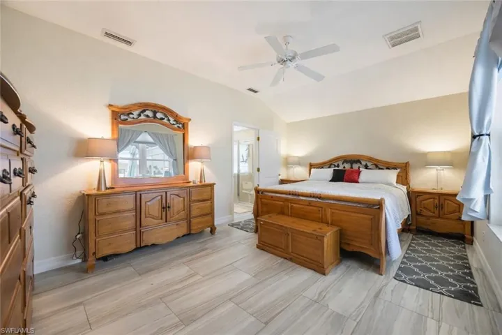 Bedroom with lofted ceiling, a ceiling fan, and connected bathroom