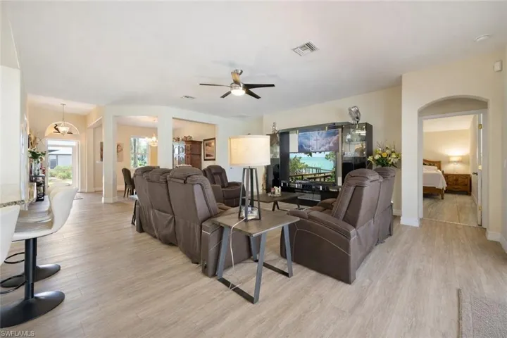 Living room with light wood-type flooring, ceiling fan, and arched walkways
