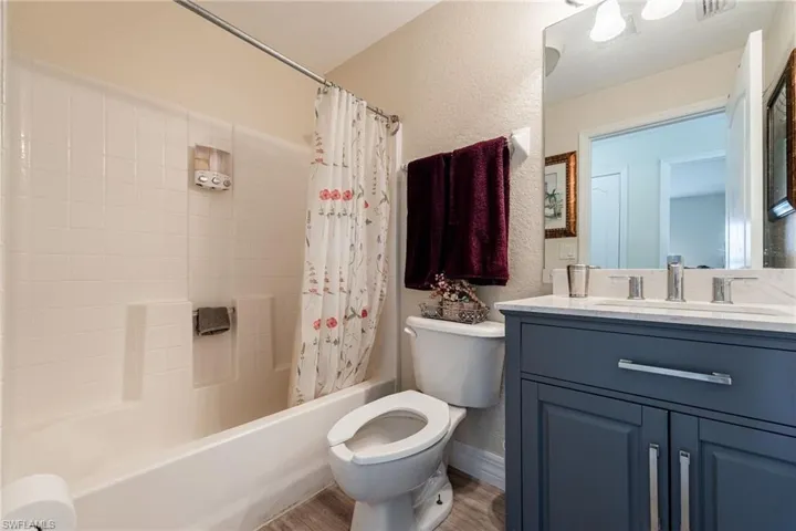 Bathroom featuring a textured wall, vanity, and shower / bath combo with shower curtain