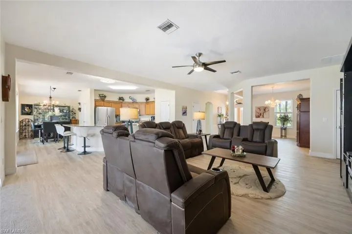 Living room with hanging lights, light wood-style floors, and ceiling fan