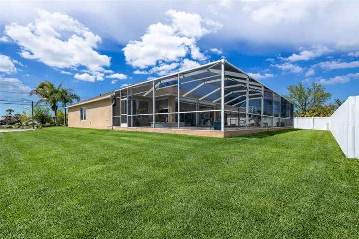 Rear view of house featuring glass enclosure, a sunroom, and stucco siding