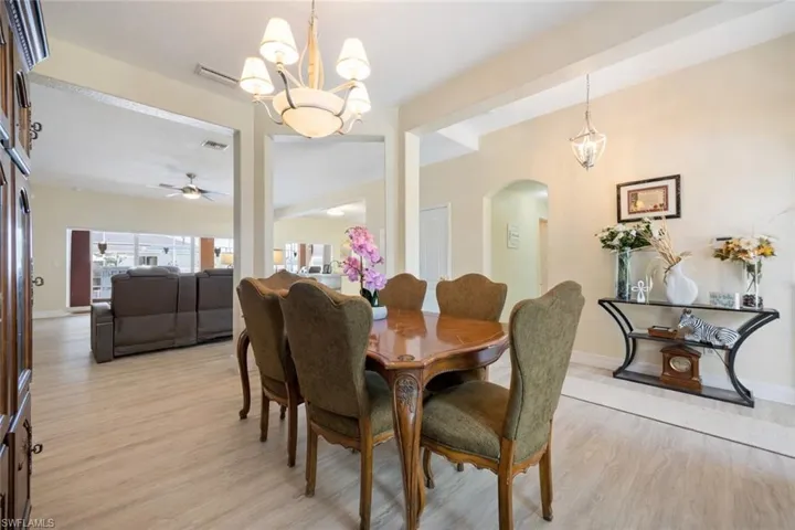 Dining room featuring a chandelier, light wood finished floors, vaulted ceiling, arched walkways, and ceiling fan