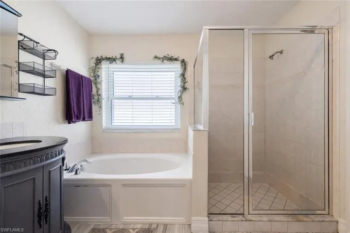 Bathroom with vanity, a stall shower, and a garden tub