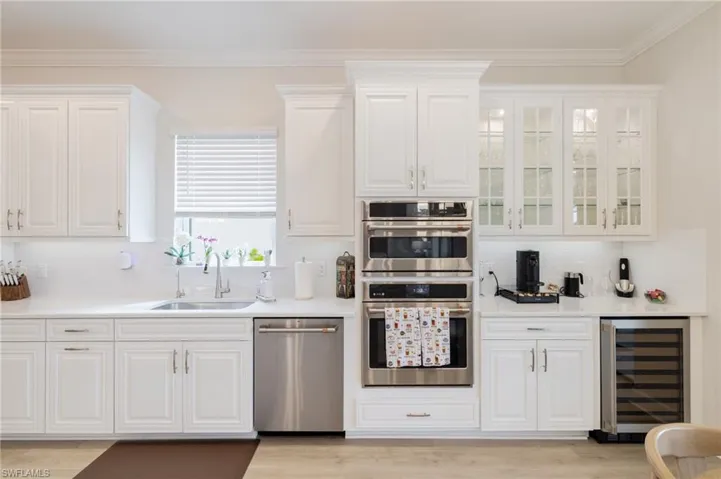 Kitchen featuring white cabinetry, stainless steel appliances, decorative backsplash, and ornamental molding