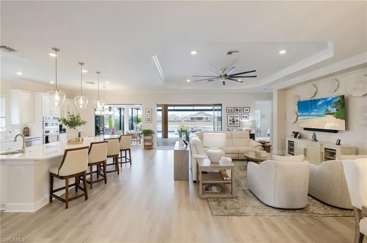 Living room with light wood finished floors, ornamental molding, a ceiling fan, and recessed lighting