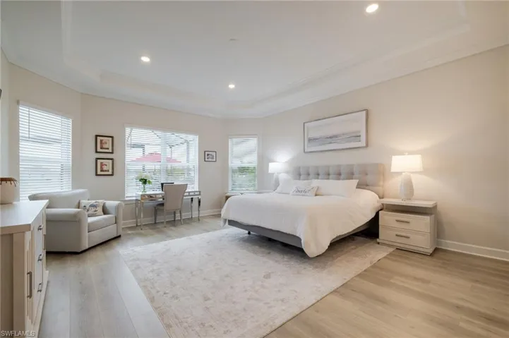 Bedroom featuring light wood finished floors, recessed lighting, crown molding, and a raised ceiling